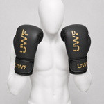 Gants de boxe UWT noir et or portés dans le bon sens par un mannequin blanc sans visage